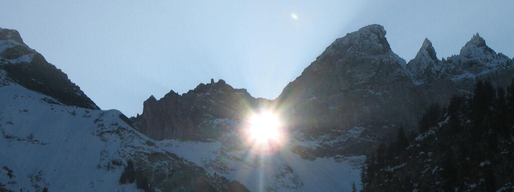 Sun shines from behind mountains