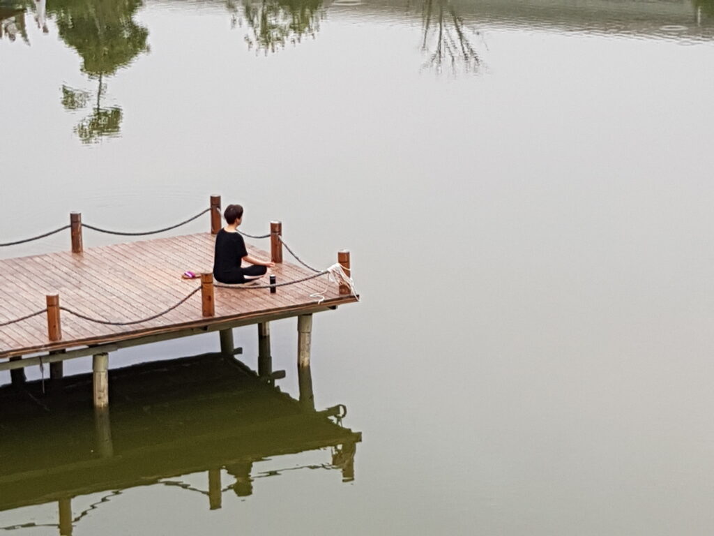 A person meditates at the water